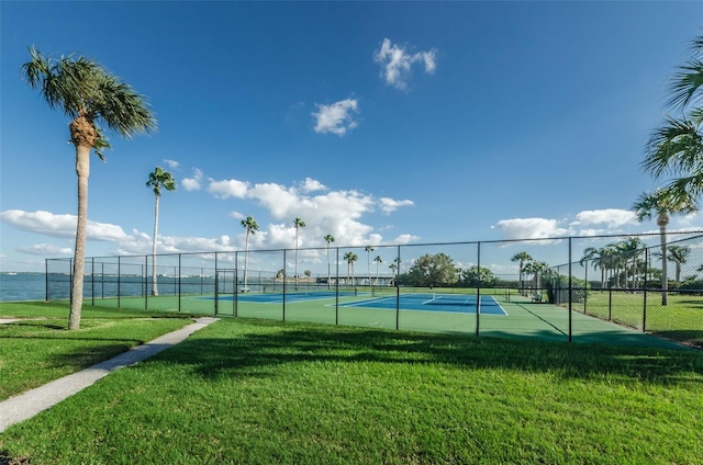 view of sport court featuring a lawn and a water view