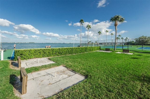 view of home's community featuring a yard, tennis court, and a water view