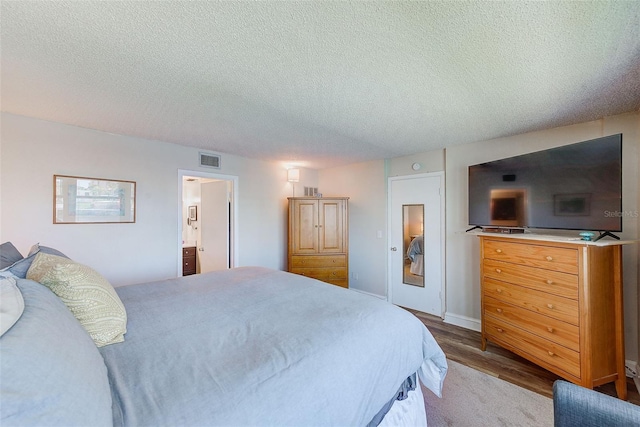 bedroom featuring hardwood / wood-style flooring, connected bathroom, and a textured ceiling