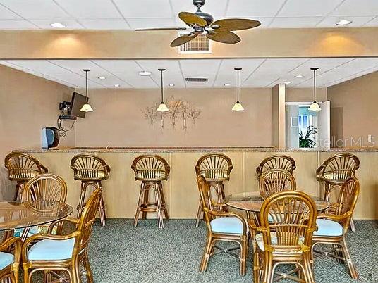 bar featuring ceiling fan, decorative light fixtures, a paneled ceiling, and carpet