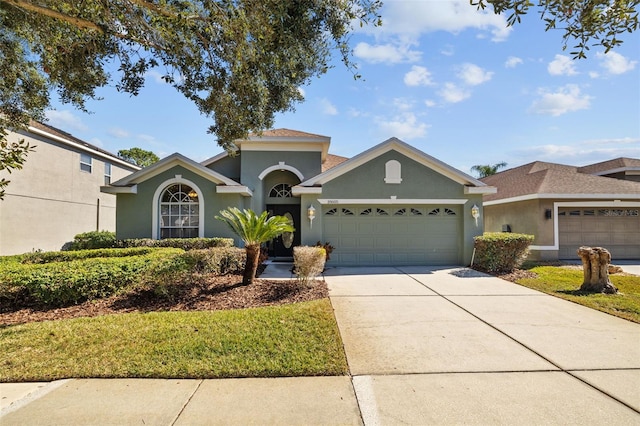 view of front of home featuring a garage, concrete driveway, a front lawn, and stucco siding