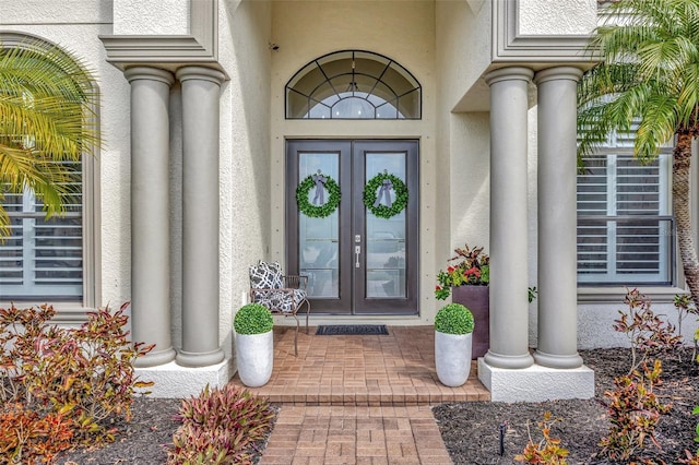 view of exterior entry featuring french doors and stucco siding