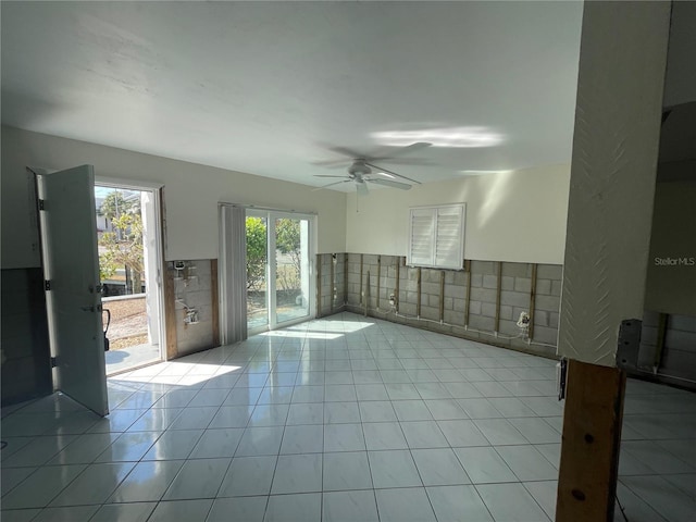 unfurnished room with ceiling fan, light tile patterned floors, and tile walls