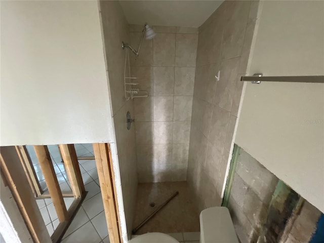 bathroom with toilet, tile patterned flooring, and a tile shower