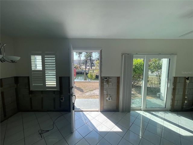 doorway featuring a water view, light tile patterned floors, and a wealth of natural light