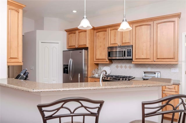 kitchen featuring light stone counters, hanging light fixtures, appliances with stainless steel finishes, kitchen peninsula, and decorative backsplash