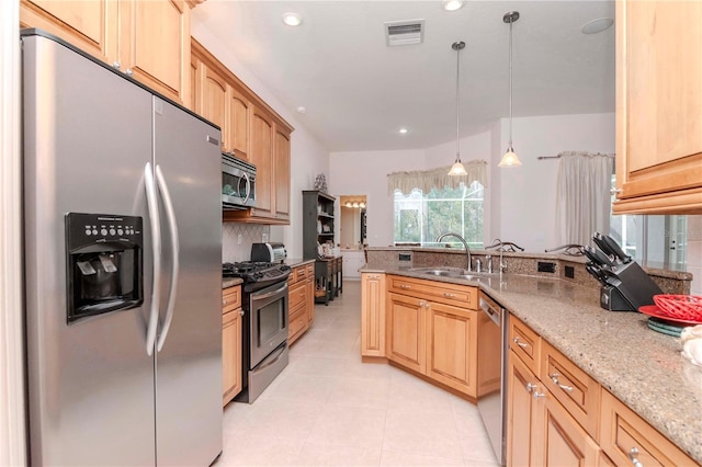 kitchen featuring sink, light stone counters, decorative light fixtures, light brown cabinets, and appliances with stainless steel finishes