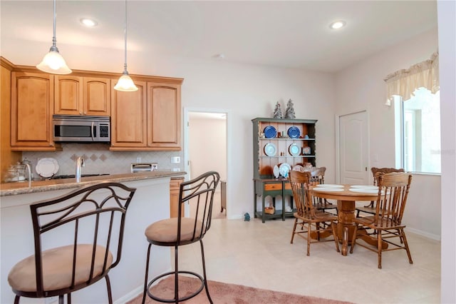 kitchen with pendant lighting, light stone countertops, and decorative backsplash