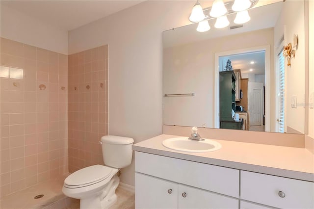 bathroom with vanity, tiled shower, tile patterned floors, and toilet