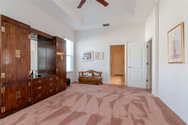 carpeted bedroom featuring ceiling fan and a raised ceiling