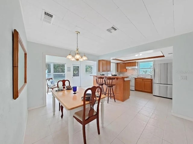 tiled dining space featuring an inviting chandelier and a raised ceiling