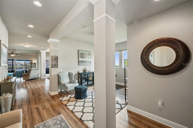 living room with hardwood / wood-style floors, ceiling fan, and ornate columns