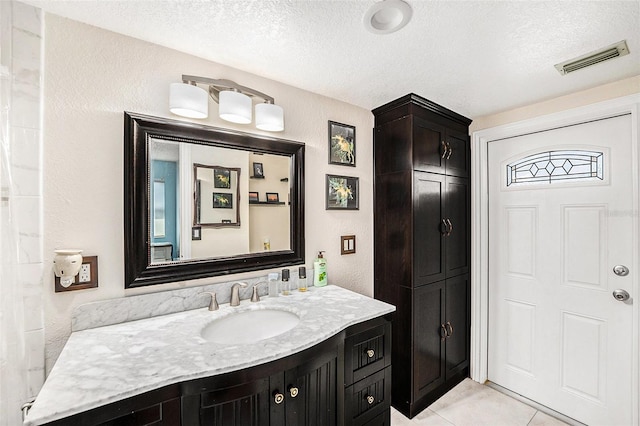 bathroom with tile patterned floors, vanity, and a textured ceiling