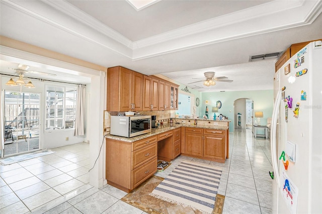 kitchen featuring ceiling fan, a tray ceiling, light tile patterned flooring, kitchen peninsula, and white fridge