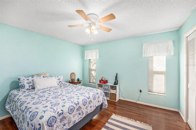 bedroom featuring ceiling fan, a textured ceiling, dark hardwood / wood-style flooring, and a closet