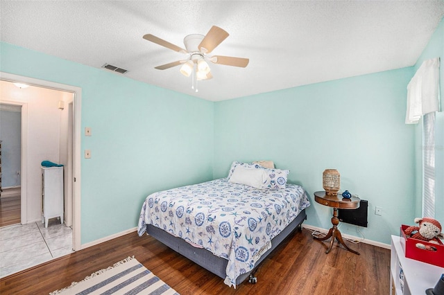 bedroom featuring ceiling fan, a textured ceiling, and dark hardwood / wood-style flooring