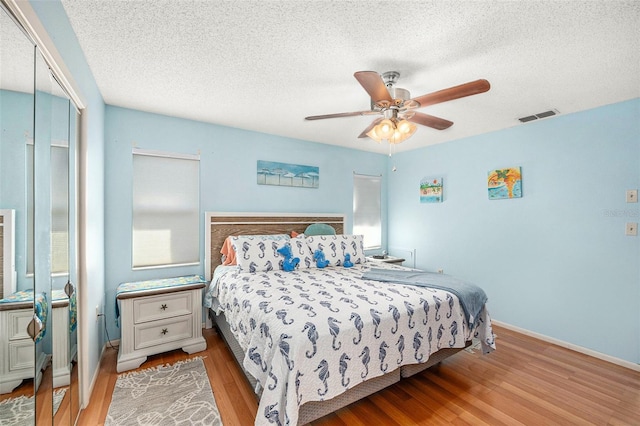 bedroom featuring ceiling fan, a closet, a textured ceiling, and light wood-type flooring