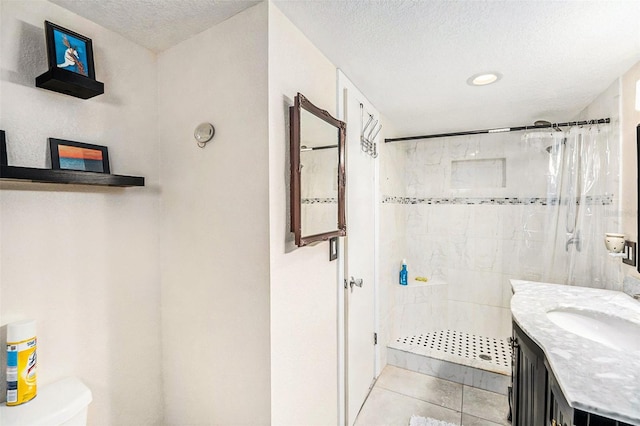 bathroom featuring tile patterned flooring, vanity, a textured ceiling, toilet, and walk in shower