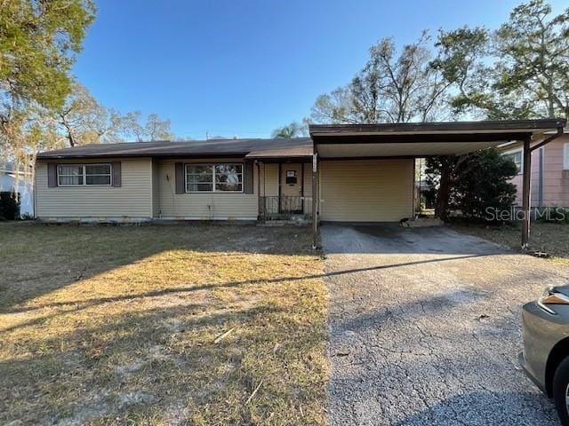 ranch-style house with driveway, a carport, and a front yard