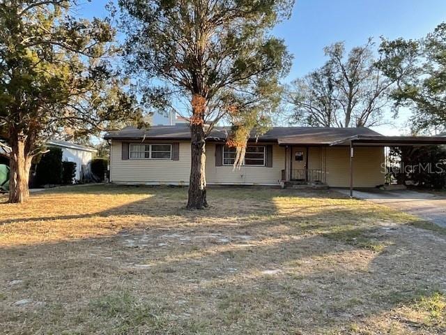 ranch-style home featuring driveway, an attached carport, and a front lawn