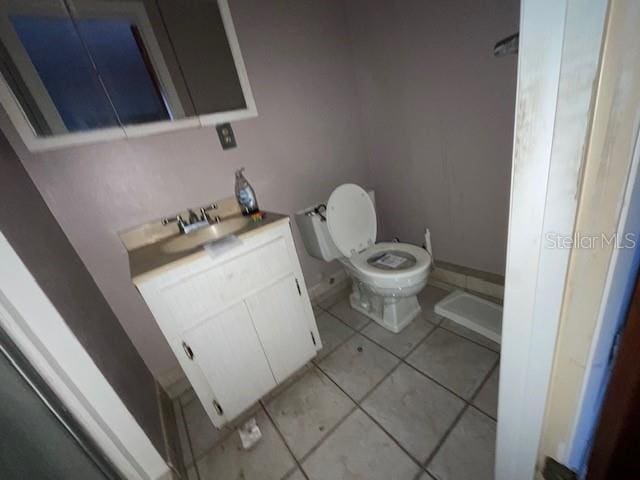 half bathroom featuring toilet, tile patterned flooring, and vanity