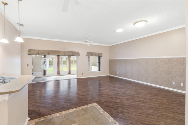 unfurnished living room featuring dark hardwood / wood-style flooring, ornamental molding, and ceiling fan