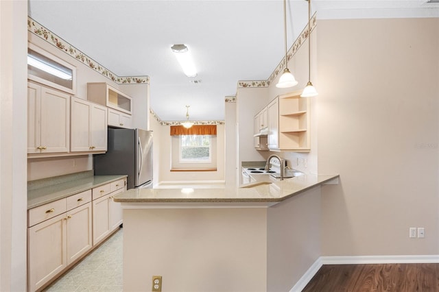 kitchen featuring stainless steel refrigerator, kitchen peninsula, and pendant lighting