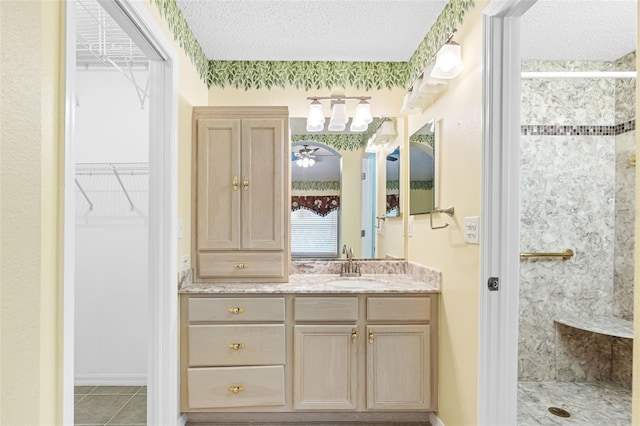 bathroom with vanity, a textured ceiling, tile patterned floors, and a shower