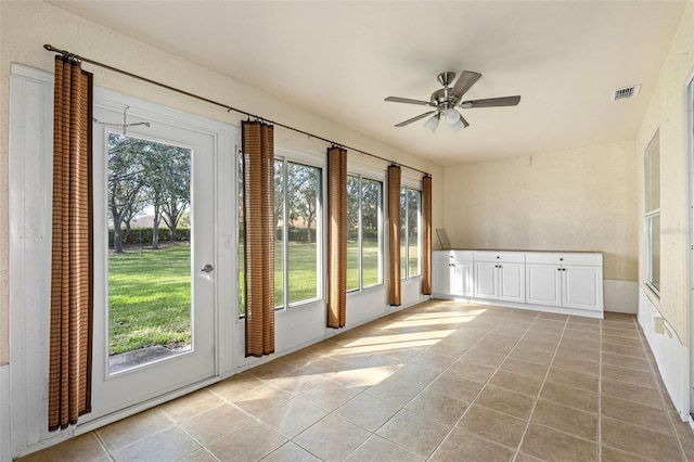 doorway featuring ceiling fan and light tile patterned flooring