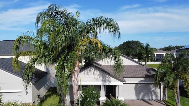 exterior space featuring stucco siding, driveway, roof with shingles, and a garage