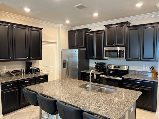 kitchen with dark cabinetry, light tile patterned floors, stainless steel appliances, and a sink