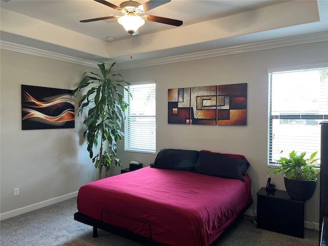 carpeted bedroom with a tray ceiling, ceiling fan, baseboards, and ornamental molding