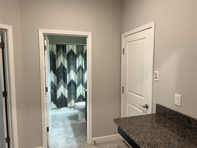 hall featuring baseboards and light tile patterned flooring