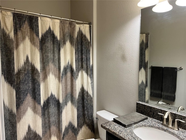 bathroom with toilet, a textured wall, vanity, and a shower with shower curtain