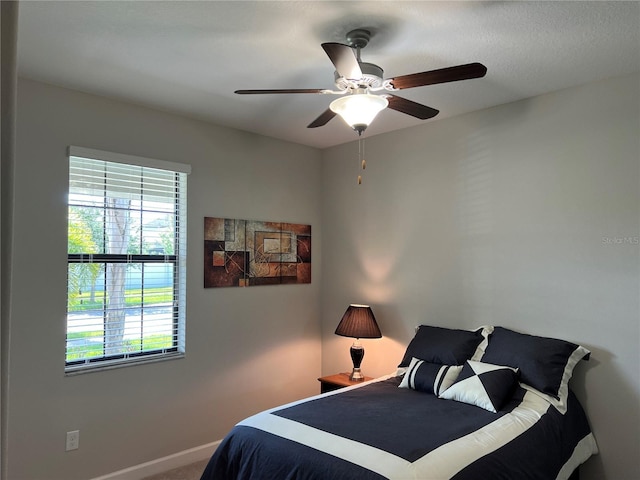 carpeted bedroom featuring a ceiling fan, baseboards, and multiple windows