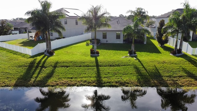 view of front facade with a fenced backyard, a front lawn, and a water view