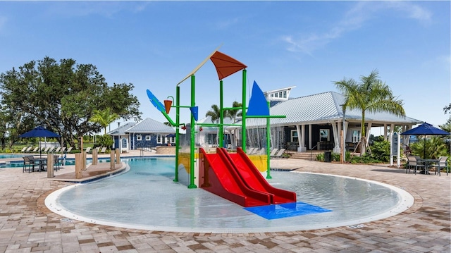 view of playground with a water play area, a community pool, and a patio area