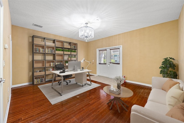 office with a notable chandelier, wood-type flooring, and a textured ceiling