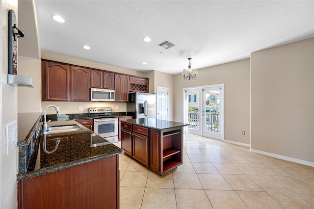 kitchen with sink, stainless steel appliances, a center island, decorative light fixtures, and french doors