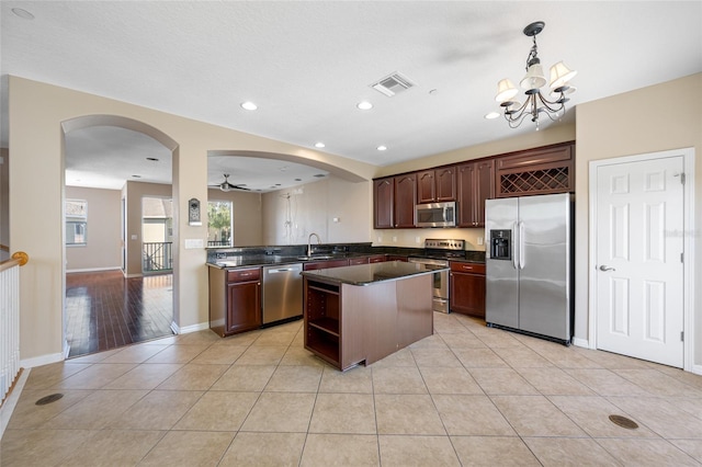 kitchen featuring decorative light fixtures, dark brown cabinets, light tile patterned floors, appliances with stainless steel finishes, and kitchen peninsula