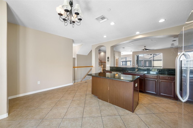 kitchen featuring sink, light tile patterned floors, stainless steel refrigerator, and a kitchen island