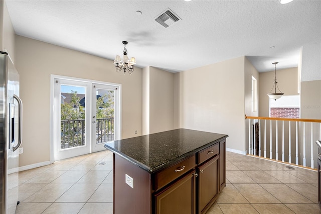 kitchen featuring light tile patterned floors, pendant lighting, dark stone counters, and stainless steel fridge with ice dispenser