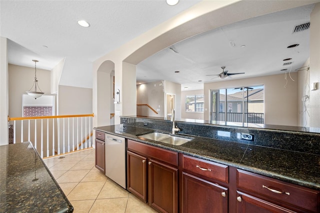 kitchen featuring sink, decorative light fixtures, dark stone countertops, light tile patterned floors, and stainless steel dishwasher