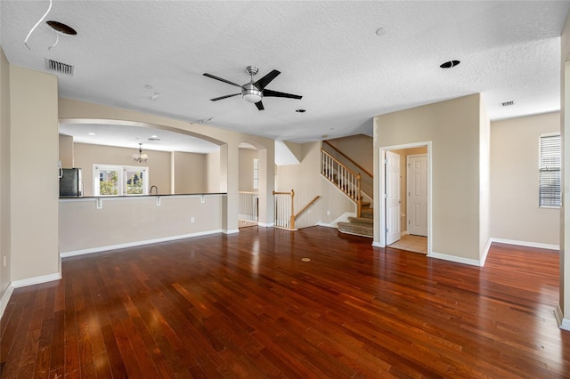 unfurnished living room with wood-type flooring, ceiling fan with notable chandelier, and a textured ceiling