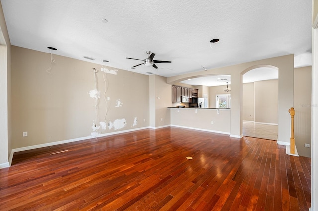 unfurnished living room with hardwood / wood-style flooring, ceiling fan, and a textured ceiling