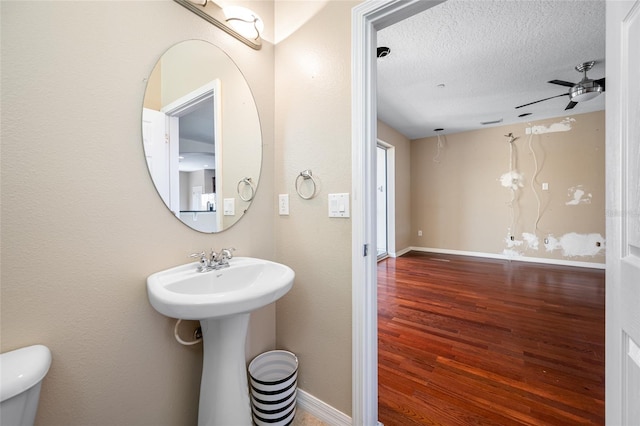 bathroom with ceiling fan, wood-type flooring, toilet, and a textured ceiling