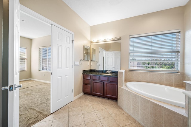 bathroom featuring vanity, a relaxing tiled tub, and tile patterned floors