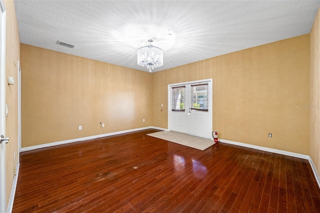 unfurnished room featuring hardwood / wood-style flooring, a textured ceiling, and an inviting chandelier