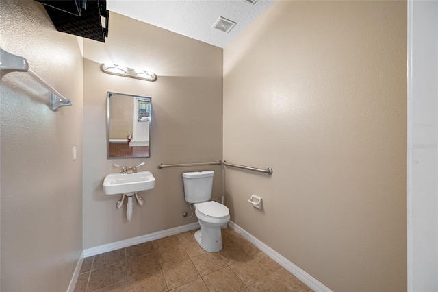 bathroom with tile patterned floors, toilet, sink, and a textured ceiling