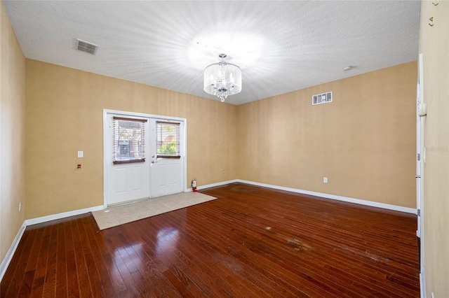 unfurnished room with wood-type flooring, a notable chandelier, and a textured ceiling